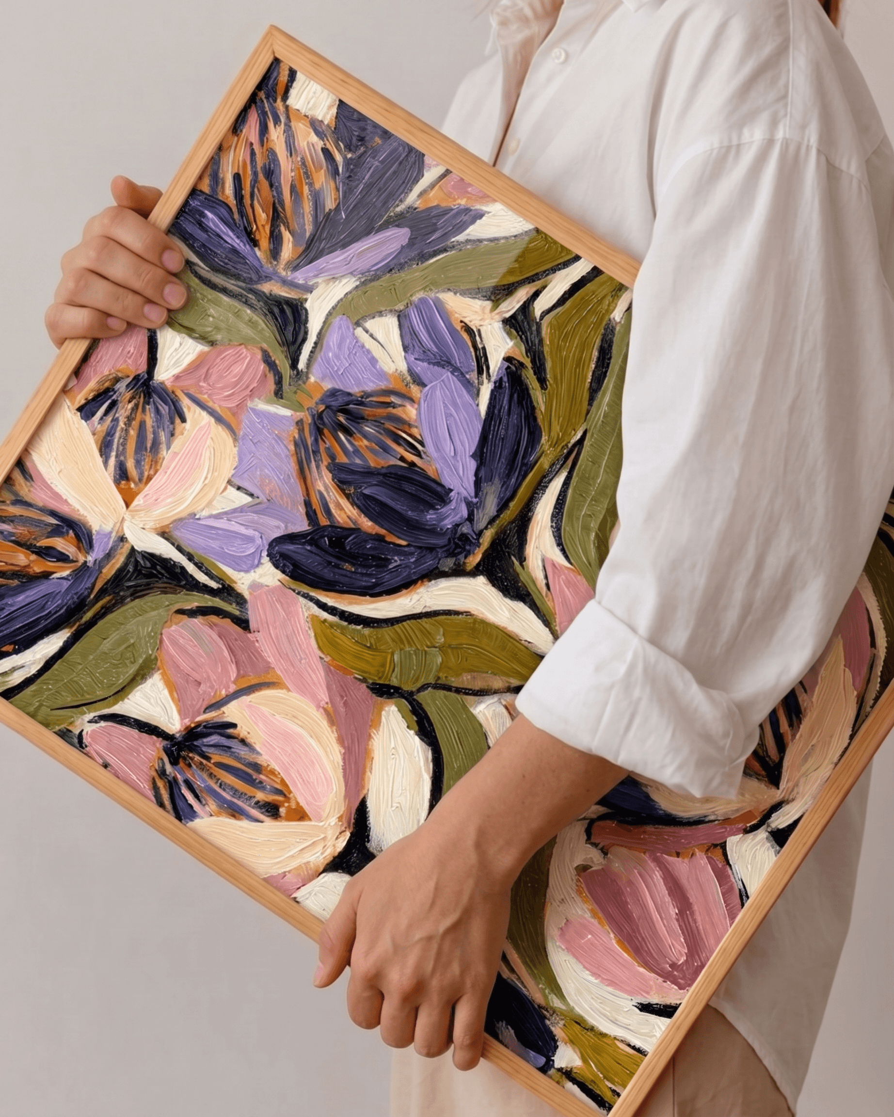 A person holding a framed original floral painting produced by Acrylic